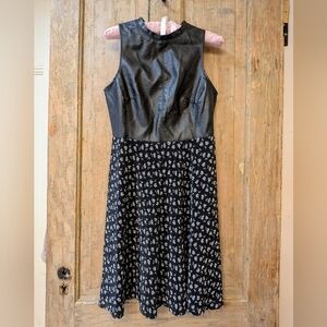 Tailored black dress with faux leather bodice and pleated skirt